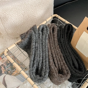 Thick knitted thermal socks in black and brown displayed in a decorative metal basket