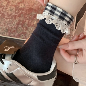Détail du revers à carreaux gris et de la bordure en dentelle blanche des chaussettes JK
