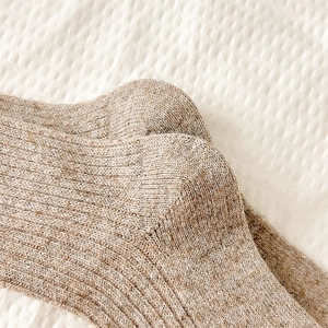 Macro shot of thick beige ribbed knit wool socks showing high-quality texture and fabric