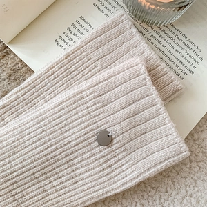 Close-up of cream knit wool socks with rib texture and decorative metal button detail
