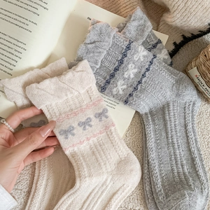 Detailed view of ribbed wool socks with knitted bow patterns and wavy cuffs in home setting