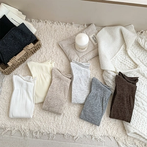 Detailed knit texture of eight assorted color crew socks in a cozy home setting