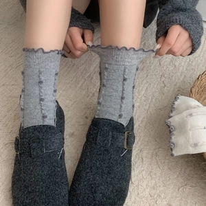 Detailed close-up of grey wool blend knit socks featuring delicate ruffled lettuce edges