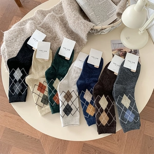Flat lay of seven colorful argyle pattern wool socks with cozy home background props