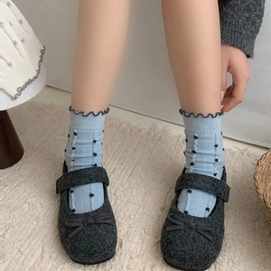 Dark grey wool Mary Jane shoes with bows and blue polka dot ruffle socks on beige rug