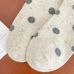 Macro detail of the warm beige knitted wool sock with gray polka dots and mixed yarn texture