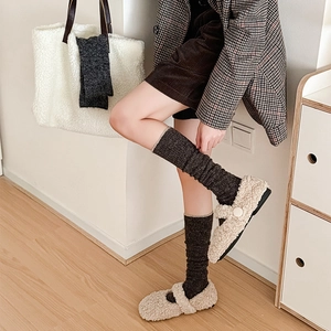 Close-up of off-white faux fur Mary Jane flats paired with thick grey knit calf socks