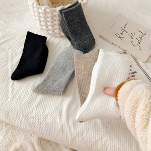 Close-up of thick wool knit socks in neutral tones with minimalist vertical ribbing details