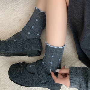Japanese style polka dot wool socks and grey Mary Jane flats on a plush carpet