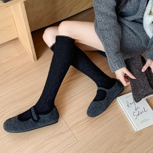 Detailed texture of thick black knit socks paired with grey wool Mary Jane flat shoes