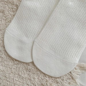 Detailed close-up of white cotton crew sock toe with reinforced stitching and rib texture
