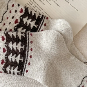 Detail of vintage Christmas tree and heart knit patterns on warm beige crew socks