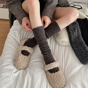 Detail of dark grey knitted calf socks paired with cozy beige Mary Jane plush flats