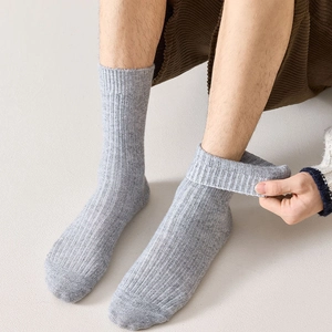 Detail of light gray ribbed wool socks showing elastic cuff and vertical knit texture