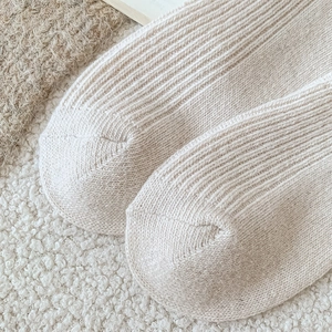 Close-up of cream white wool socks showing thick vertical ribbed knit texture for winter