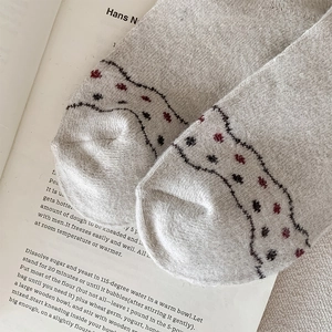 Macro detail of thick knitted crew socks with red polka dots and wavy patterned toe design