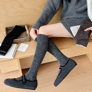 Detail of thick grey knit thigh high socks paired with matching mary jane flats