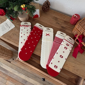 Close-up of five pairs of red and cream floral mid-calf socks with festive patterns