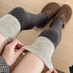 Nahaufnahme dicker Strickstulpen in Grau und Beige mit Vintage-Wildlederschuhen kombiniert