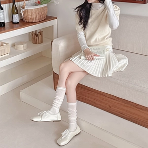 Cozy lifestyle view of white slouch socks paired with ballet flats and a pleated skirt
