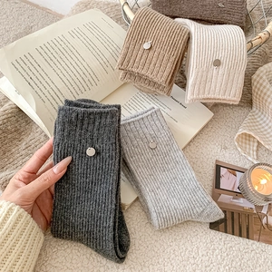 Detail of ribbed knit wool socks in autumn colors with elegant metal pendant charms