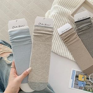Detailed shot of four pairs of striped crew socks in pastel blue, grey, khaki and charcoal