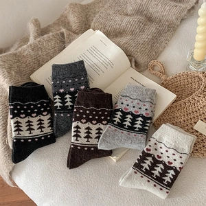 Detail view of five pairs of thick knitted wool socks with Nordic forest tree patterns