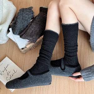 Chic grey felt Mary Jane shoes with black ribbed knee-high socks on a cozy wooden floor