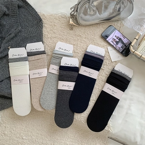 Detail of six pairs of ribbed cotton socks with striped cuffs in various neutral colors