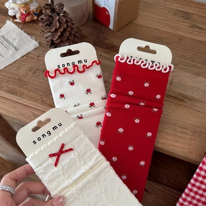 Detail of floral socks with red bows, knit patterns and delicate ruffle trim on wood