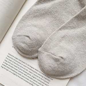 Close-up of soft beige wool knit socks on an open book for cozy winter style