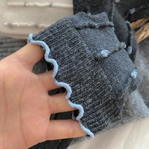 Detail of grey wool sock featuring elastic light blue ruffled edge and thick knit texture