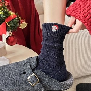 Detail of navy knit wool socks with Santa embroidery and festive holiday decor