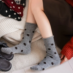 Gray knitted crew socks with black polka dots and stylish rolled edges for women