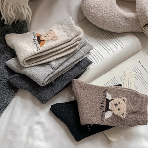 Detailed knit texture of five colorful winter socks with cute teddy bear embroidery