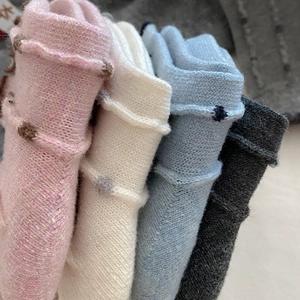 Close-up of four colors of knitted wool socks with textured ribbing and cute pom-poms