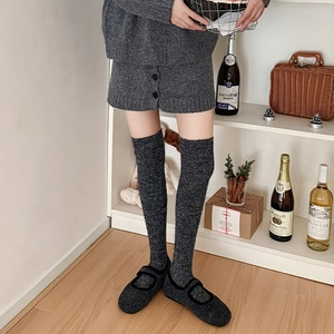 Detailed knit texture of dark gray over-the-knee socks and matching knit flat shoes