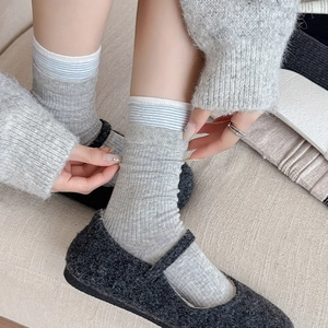 Detailed view of grey ribbed mid-calf socks with light blue stripes and Mary Jane shoes