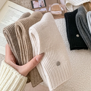 Detail of ribbed knit wool socks with shell button accent on creamy white fabric