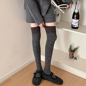 Detail von warmen Overknee-Socken aus grauem und braunem Strickstoff für den Winter