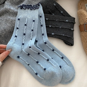 Detail of wool socks with polka dots, vertical stripes and ruffled lace cuffs in soft knit