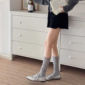 Japanese style grey slouch socks paired with silver Mary Jane shoes in a soft interior setting