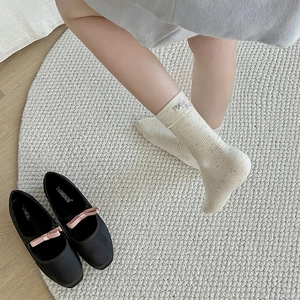 Détail d'une chaussette en maille crème mouchetée avec broderie et chaussures Mary Jane