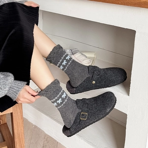 Close-up of wool knit socks with white bow jacquard pattern and dark grey felt clogs