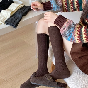 Detail of dark brown knit knee-high socks featuring vintage hollowed-out jacquard patterns