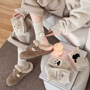 Détail de chaussettes en laine blanc cassé avec motifs d'animaux mignons et doublure douce