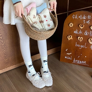 Detail von warmen Flauschsocken mit süßen Katzen- und Bärenmustern und Schleifen
