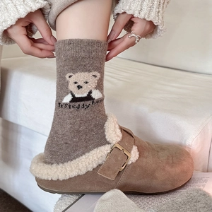 Close-up of cozy brown knit bear socks paired with warm faux fur lined mule slippers