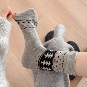 Detail of elastic cuff on thick knitted grey crew socks with festive pine tree patterns