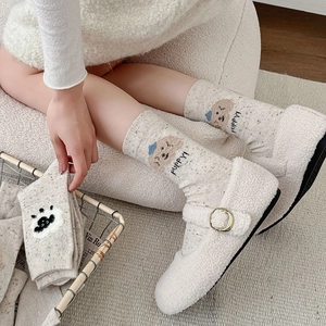 Détail de chaussettes en laine crème avec broderie chiot et texture de tricot moucheté